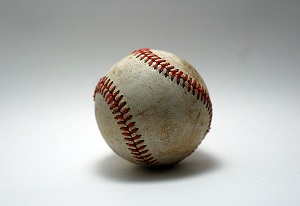 A well-used baseball sitting on a white background